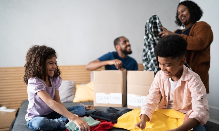 Parents with children sorting out clothes in boxes to donate at home